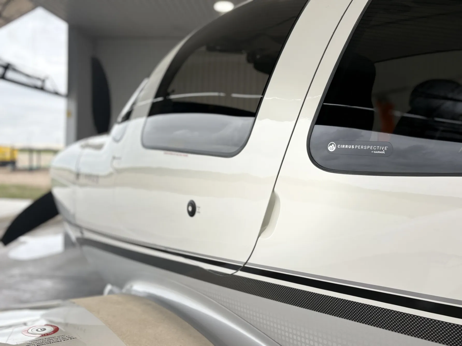 Deep-gloss white Cirrus fuselage and tinted cabin window in the hangar